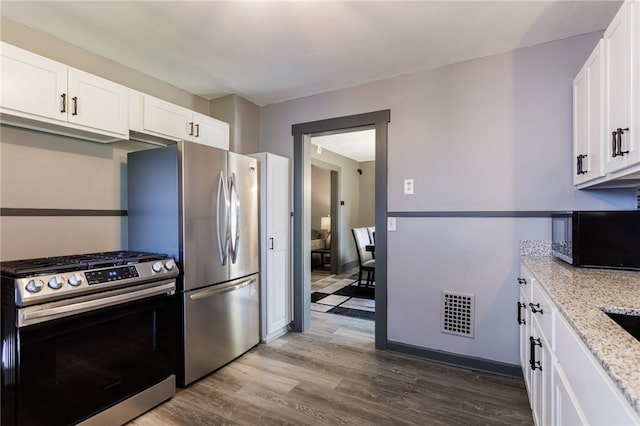 74 Everett St, Greece, NY 14615 - kitchen with appliances with stainless steel finishes, dark wood finished floors, light stone countertops, white cabinetry, and baseboards
