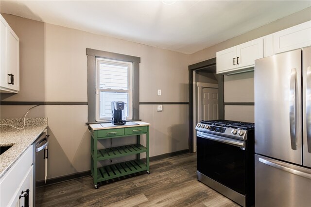 74 Everett St, Greece, NY 14615 - kitchen with stainless steel appliances, dark wood-type flooring, light stone countertops, white cabinets, and baseboards