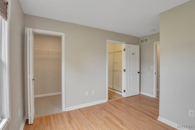 836 Upper Mountain Rd, Lewiston, NY 14092 - unfurnished bedroom featuring light wood-type flooring, a walk in closet, baseboards, ensuite bath, and a closet