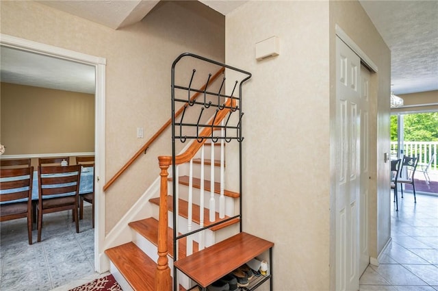 53 Toni Ter, Chili, NY 14624 - stairway featuring a chandelier, tile patterned flooring, and a textured ceiling