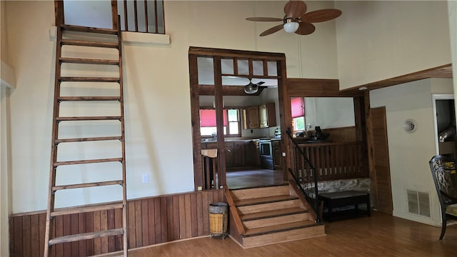 3976 Eddy Rd, Thurston, NY 14801 - stairway with a ceiling fan, wood finished floors, a wainscoted wall, a towering ceiling, and wood walls