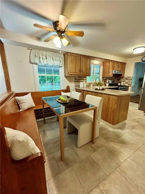 30 Sibley Dr, West Seneca, NY 14224 - kitchen featuring stainless steel stove, brown cabinets, a peninsula, a ceiling fan, and under cabinet range hood