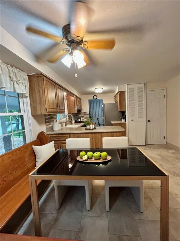 30 Sibley Dr, West Seneca, NY 14224 - kitchen with freestanding refrigerator, a ceiling fan, a peninsula, brown cabinetry, and light countertops