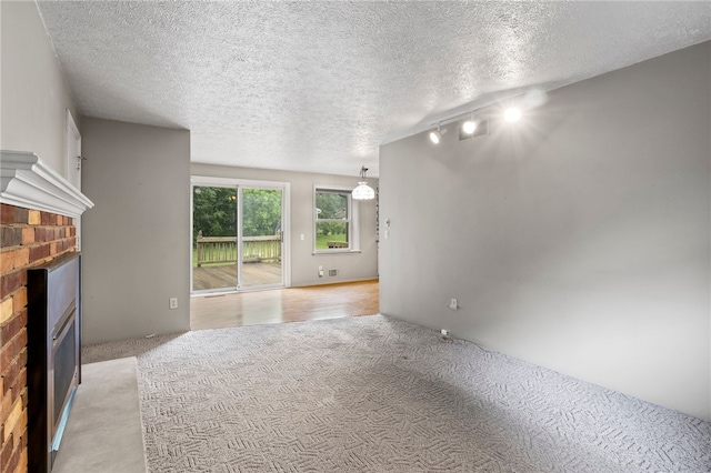 69 Tree Brook Dr, Penfield, NY 14625 - unfurnished living room featuring a fireplace, light colored carpet, track lighting, and a textured ceiling
