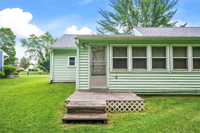 176 Wildbriar Rd, Henrietta, NY 14623 - view of exterior entry featuring a yard, a shingled roof, and a wooden deck