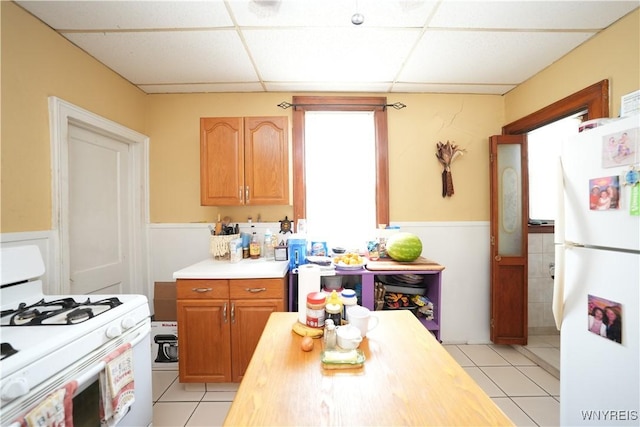 132 Weiss St, Buffalo, NY 14206 - kitchen with white appliances, a paneled ceiling, light tile patterned flooring, wainscoting, and light countertops