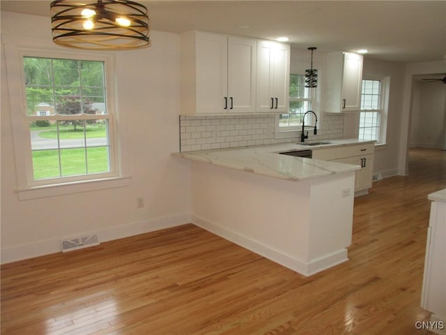 kitchen featuring a sink, baseboards, white cabinetry, and light wood-style floors