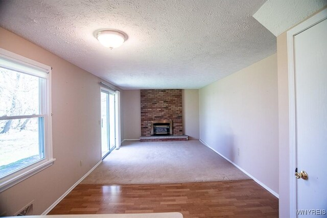 18 Tree Top Dr, Penfield, NY 14625 - unfurnished living room with wood finished floors, a textured ceiling, a fireplace, and baseboards