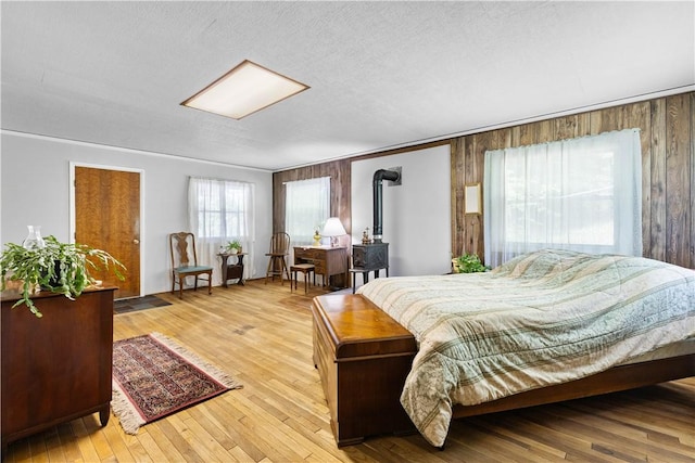 8471 Alpaugh Rd, Springwater, NY 14572 - bedroom with a wood stove, wood walls, and hardwood / wood-style floors