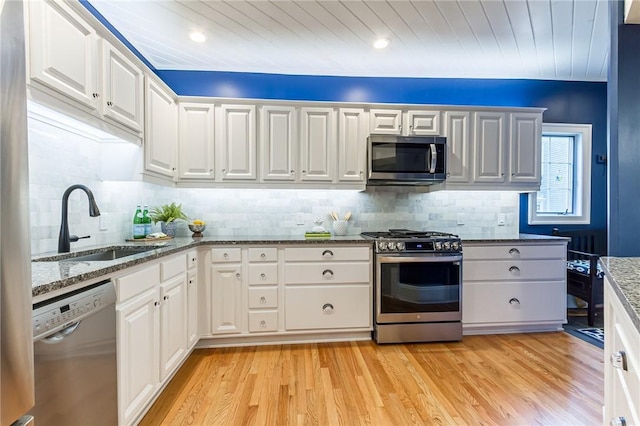 76 W Main St, Mendon, NY 14472 - kitchen with appliances with stainless steel finishes, light wood-style floors, white cabinetry, backsplash, and stone counters