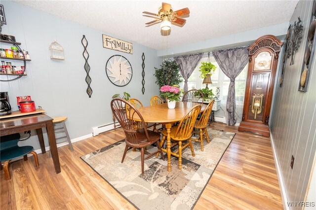 6817 Revere Dr, Evans, NY 14047 - dining room featuring light wood-style flooring, a ceiling fan, a baseboard radiator, and a textured ceiling