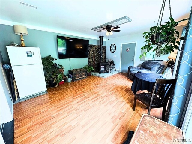 6817 Revere Dr, Evans, NY 14047 - living area featuring a wood stove, wood finished floors, and ceiling fan