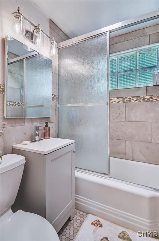 435 Elm St, Ithaca City, NY 14850 - full bathroom featuring toilet, shower / bath combination with glass door, vanity, tile walls, and tile patterned floors