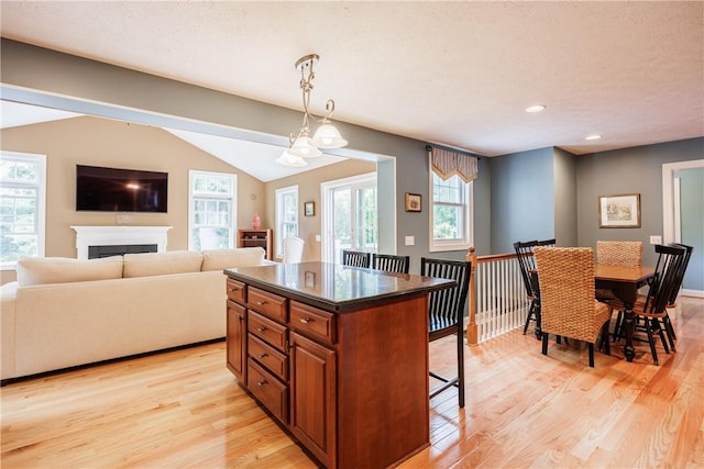 654 Lake Shore Blvd, Irondequoit, NY 14617 - kitchen with brown cabinets, light wood-style flooring, a breakfast bar area, dark countertops, and recessed lighting