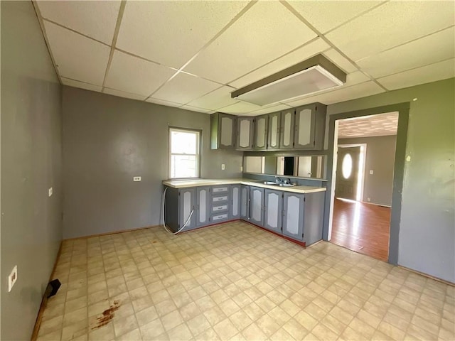 201 S Main St, Wayland, NY 14572 - kitchen featuring gray cabinetry, a paneled ceiling, light countertops, light floors, and a sink
