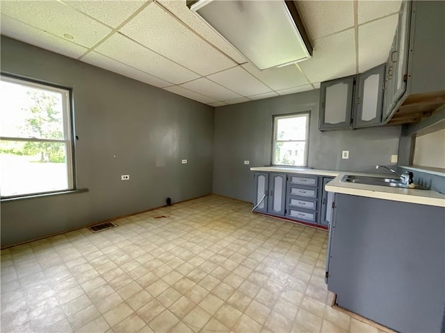201 S Main St, Wayland, NY 14572 - kitchen with a drop ceiling, gray cabinetry, light floors, light countertops, and a sink