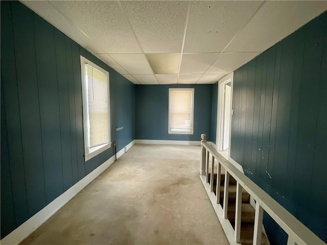 201 S Main St, Wayland, NY 14572 - spare room featuring concrete flooring, a drop ceiling, baseboards, and wood walls