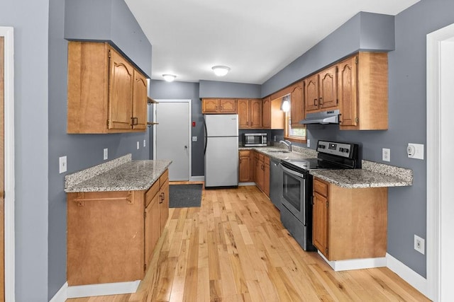 26 Prospect St, Delhi, NY 13753 - kitchen with appliances with stainless steel finishes, under cabinet range hood, a sink, light wood-style flooring, and brown cabinetry