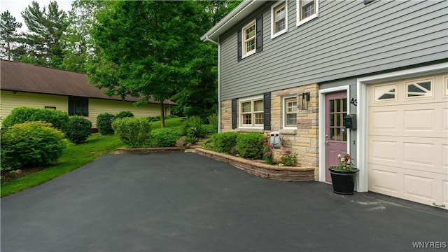 43 Larned Ln, Orchard Park, NY 14127 - view of home's exterior with a garage, stone siding, and a patio area