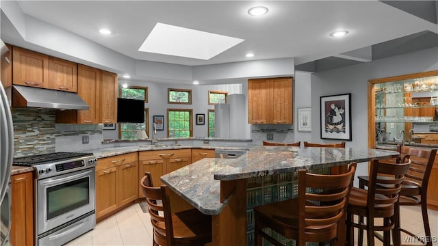 43 Larned Ln, Orchard Park, NY 14127 - kitchen featuring stainless steel gas range oven, under cabinet range hood, a skylight, brown cabinetry, and recessed lighting