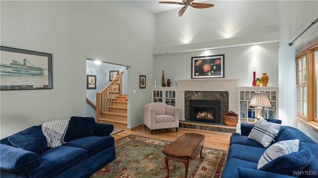 43 Larned Ln, Orchard Park, NY 14127 - living room with wood finished floors, a ceiling fan, a high ceiling, stairs, and a high end fireplace