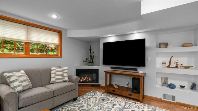 43 Larned Ln, Orchard Park, NY 14127 - living area with wood finished floors, a lit fireplace, built in features, and recessed lighting