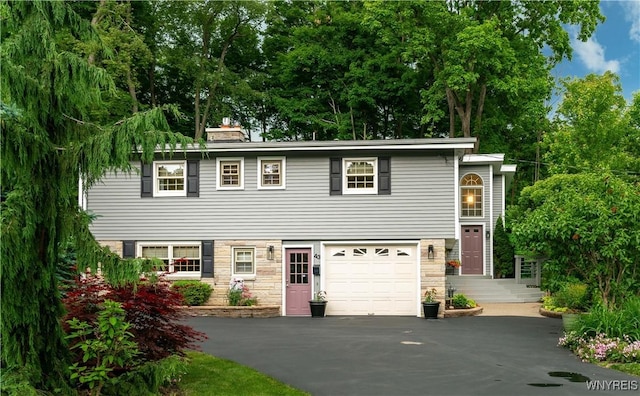 43 Larned Ln, Orchard Park, NY 14127 - view of front of home with stone siding, driveway, a chimney, and an attached garage