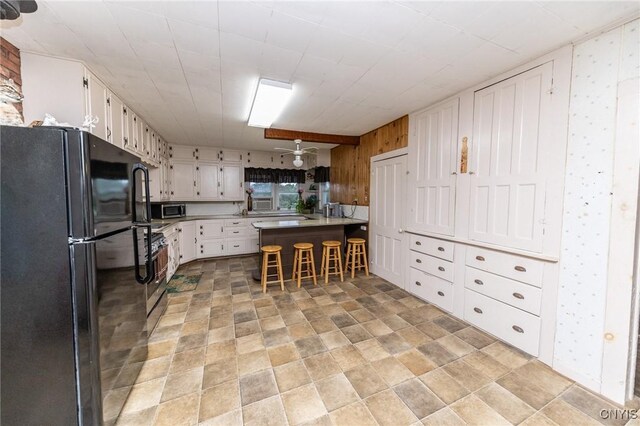 7750 State Route 812, New Bremen, NY 13367 - kitchen featuring stainless steel appliances, a peninsula, wallpapered walls, a kitchen breakfast bar, and white cabinetry