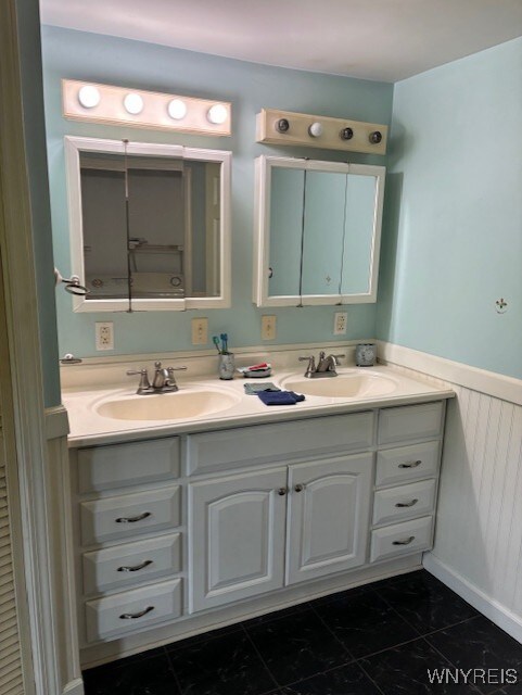 7491 S Grove Rd, Lyndon, NY 14737 - bathroom featuring double vanity, wainscoting, and marble finish flooring