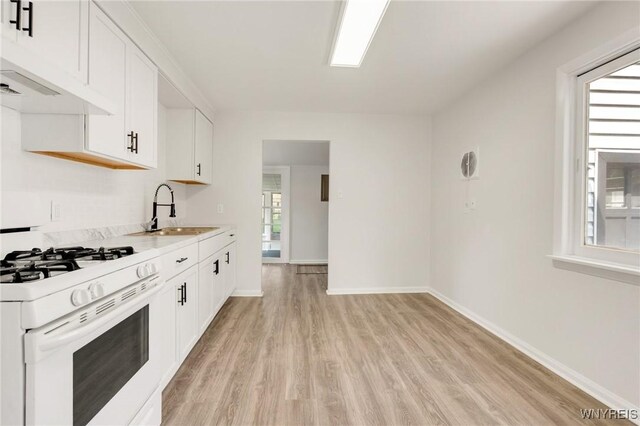126 Pryor Ave, Tonawanda, NY 14150 - kitchen featuring white gas stove, light wood-style flooring, white cabinets, light countertops, and premium range hood