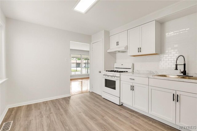 126 Pryor Ave, Tonawanda, NY 14150 - kitchen featuring white range with gas cooktop, under cabinet range hood, light wood-style flooring, light countertops, and white cabinetry