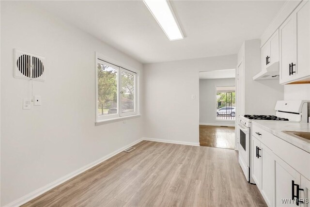126 Pryor Ave, Tonawanda, NY 14150 - kitchen featuring white range with gas cooktop, under cabinet range hood, light wood-style flooring, light countertops, and white cabinetry