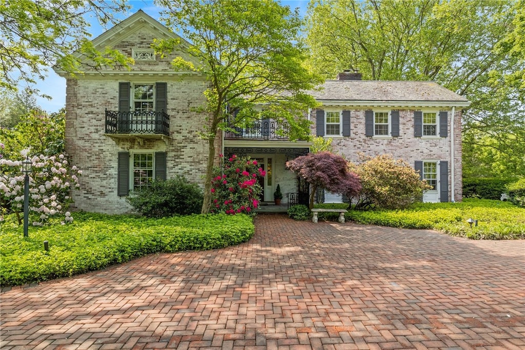 16 Mitchell Rd, Pittsford, NY 14534 - view of front facade with a balcony, brick siding, a porch, and a chimney