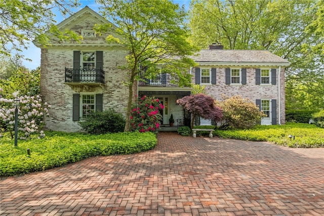 16 Mitchell Rd, Pittsford, NY 14534 - view of front facade with a balcony, brick siding, a porch, and a chimney