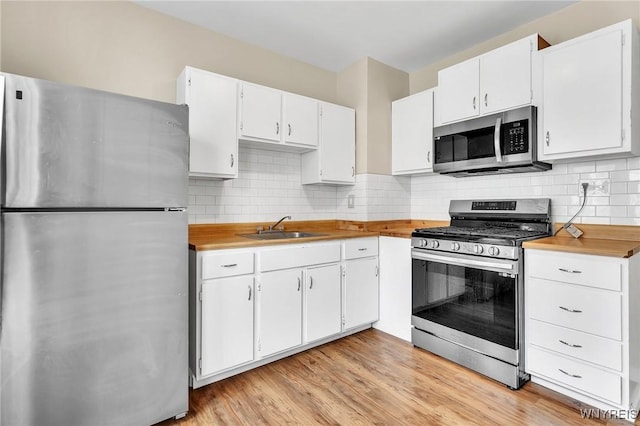 88 Rugby Rd, Buffalo, NY 14216 - kitchen featuring appliances with stainless steel finishes, white cabinets, light wood-style flooring, and decorative backsplash