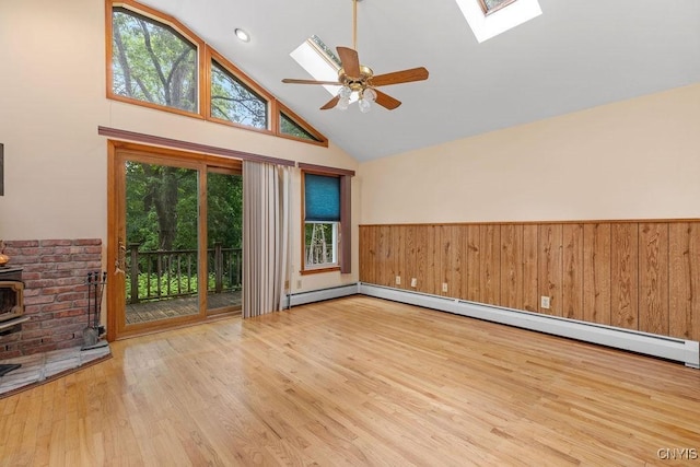 814 Oswego St, Salina, NY 13088 - empty room with a skylight, a wood stove, a wainscoted wall, high vaulted ceiling, and wood finished floors