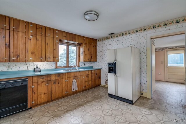 9569 Church St, Denmark, NY 13620 - kitchen with white fridge with ice dispenser, black dishwasher, brown cabinets, wallpapered walls, and light countertops