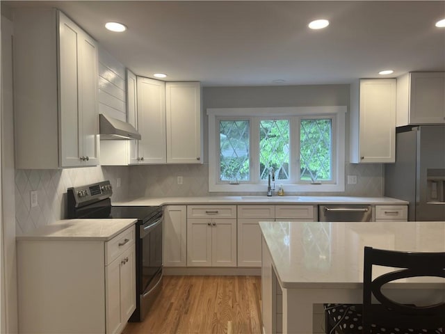 43 Harvest Rd, Perinton, NY 14450 - kitchen with appliances with stainless steel finishes, exhaust hood, light wood-type flooring, recessed lighting, and tasteful backsplash