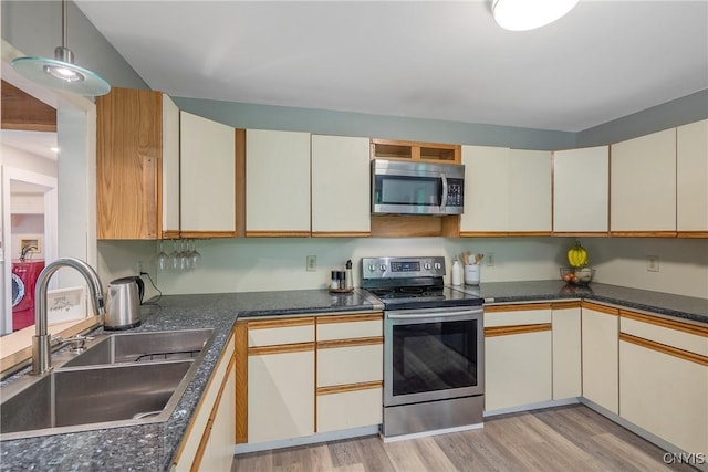 129 Quartz, Camillus, NY 13219 - kitchen featuring appliances with stainless steel finishes, separate washer and dryer, light wood finished floors, dark countertops, and cream cabinets