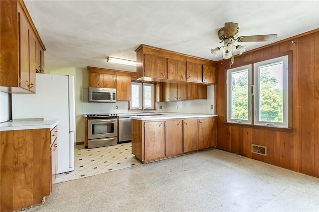 65 Meyerhill Cir E, Irondequoit, NY 14617 - kitchen with stainless steel appliances, brown cabinets, a peninsula, light countertops, and light floors