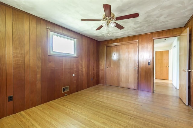 65 Meyerhill Cir E, Irondequoit, NY 14617 - unfurnished bedroom featuring a closet, wood walls, light wood finished floors, and a ceiling fan