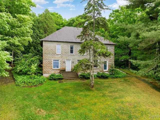 175 S Rondaxe Rd, Webb, NY 13420 - view of front of home with stone siding, a front lawn, roof with shingles, and a forest view