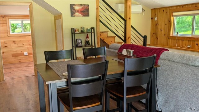 6234 Reservoir Rd, Lebanon, NY 13346 - dining area with a wall mounted air conditioner, stairway, wooden walls, and wood finished floors