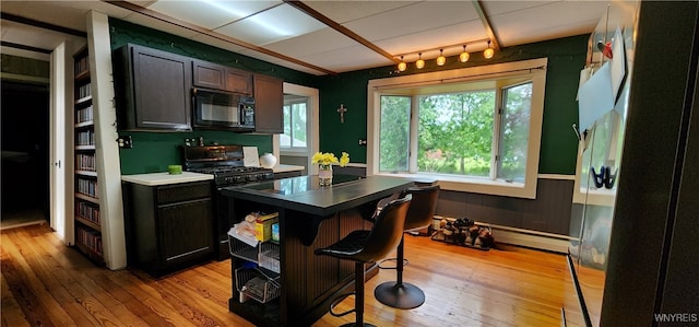 7029 Akron Rd, Lockport Town, NY 14094 - kitchen featuring black microwave, gas range oven, light wood-style floors, and a kitchen breakfast bar