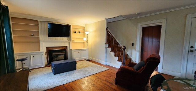 7029 Akron Rd, Lockport Town, NY 14094 - living area featuring hardwood / wood-style floors, stairs, a glass covered fireplace, and built in features
