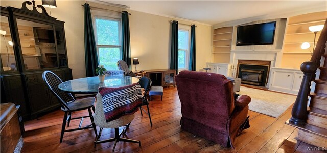 7029 Akron Rd, Lockport Town, NY 14094 - living room with wood-type flooring, a glass covered fireplace, crown molding, and built in shelves