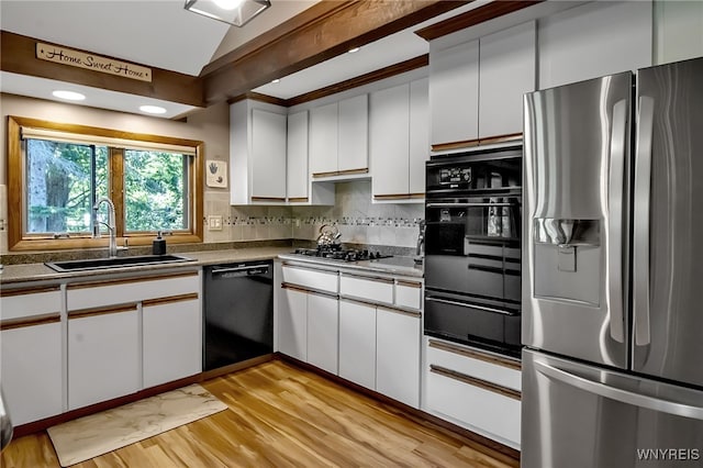 17 Quail, Orchard Park, NY 14127 - kitchen featuring black appliances, a warming drawer, vaulted ceiling, white cabinets, and tasteful backsplash
