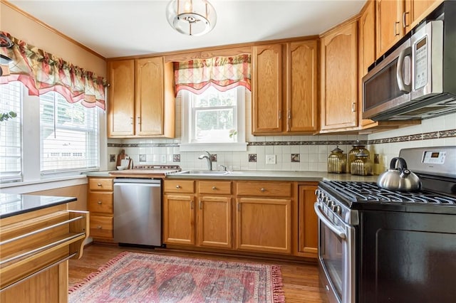 207 Wimbledon Rd, Irondequoit, NY 14617 - kitchen with appliances with stainless steel finishes, wood finished floors, decorative backsplash, light countertops, and brown cabinetry