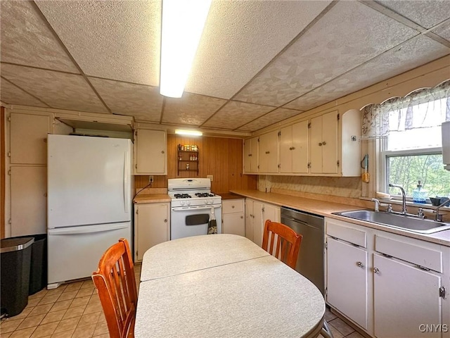 9067 Main St, Brookfield, NY 13418 - kitchen with white appliances, light countertops, a paneled ceiling, light tile patterned flooring, and wood walls