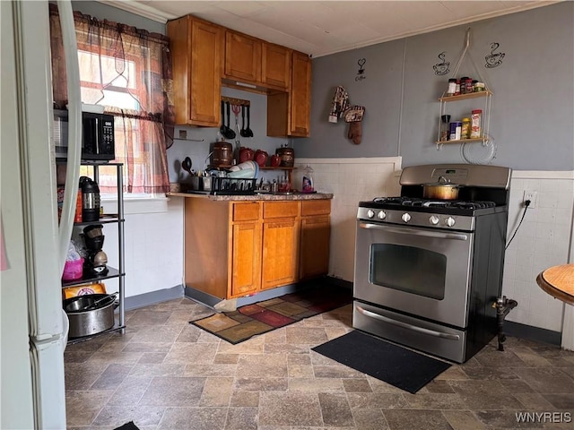 139 Weimar St, Buffalo, NY 14206 - kitchen featuring gas range, brown cabinetry, tile walls, freestanding refrigerator, and a wainscoted wall